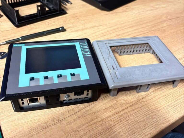 Panel dotykowy Siemens Simatic obok wydrukowanej w 3D ramki zastępczej